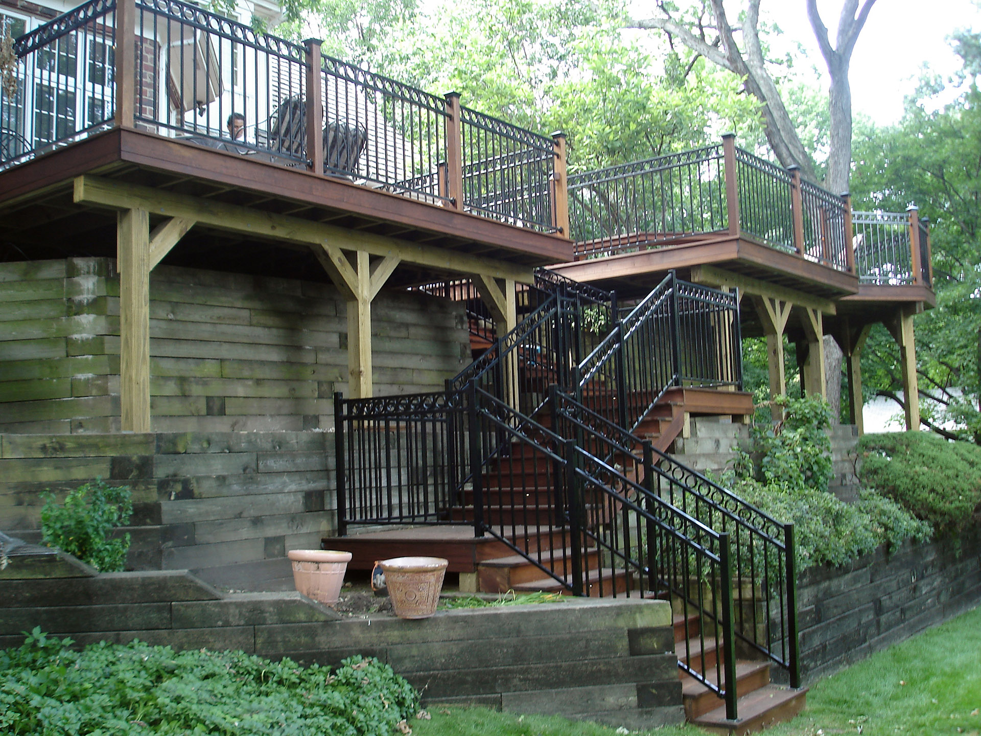 A multi-level wood deck with black metal stair railings.