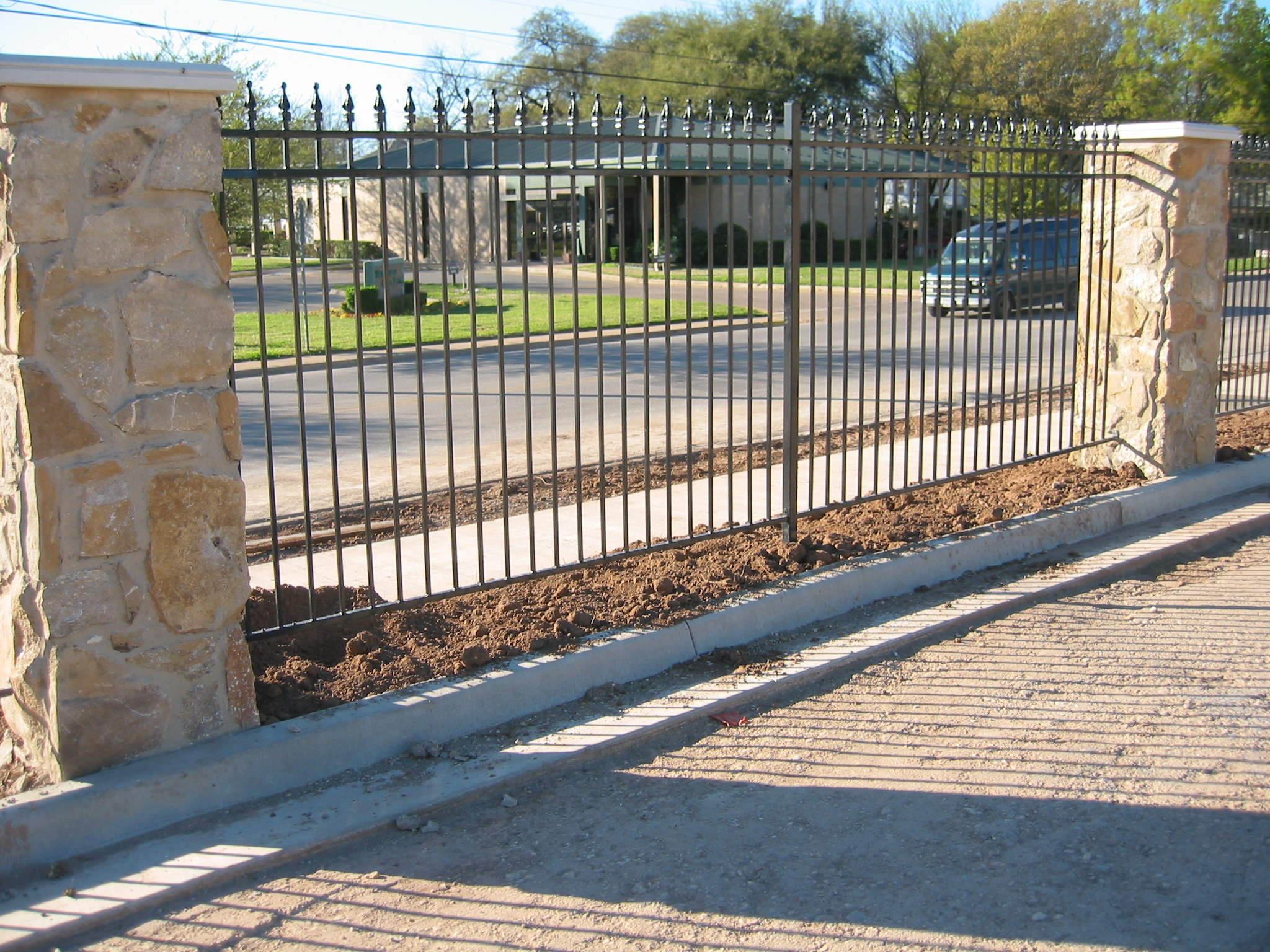 Decorative fence with a stone wall, incorporating both aluminum fencing for a modern residential look.