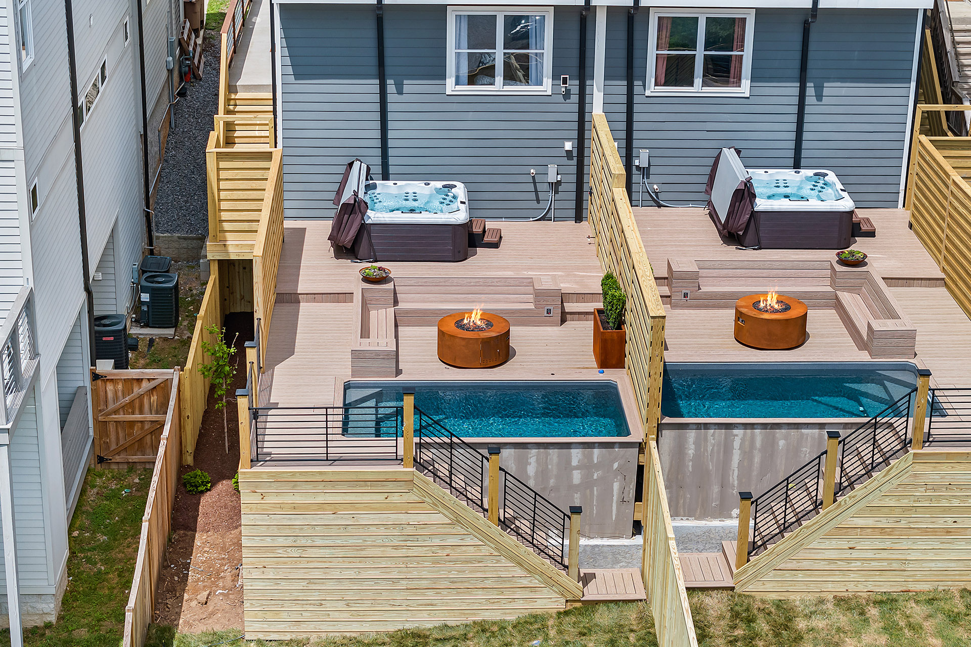 Modern duplex backyard with black steel stair railings enclosing a deck and plunge pool.