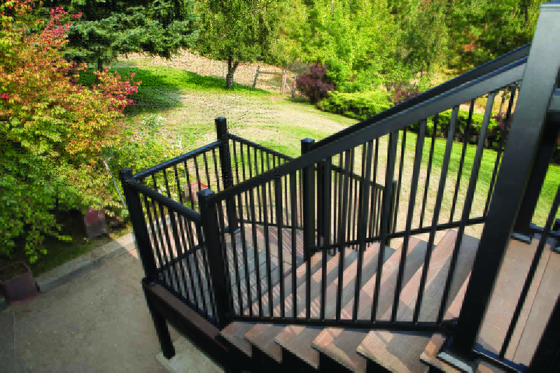 Black metal stair railing installed on a sloped backyard.