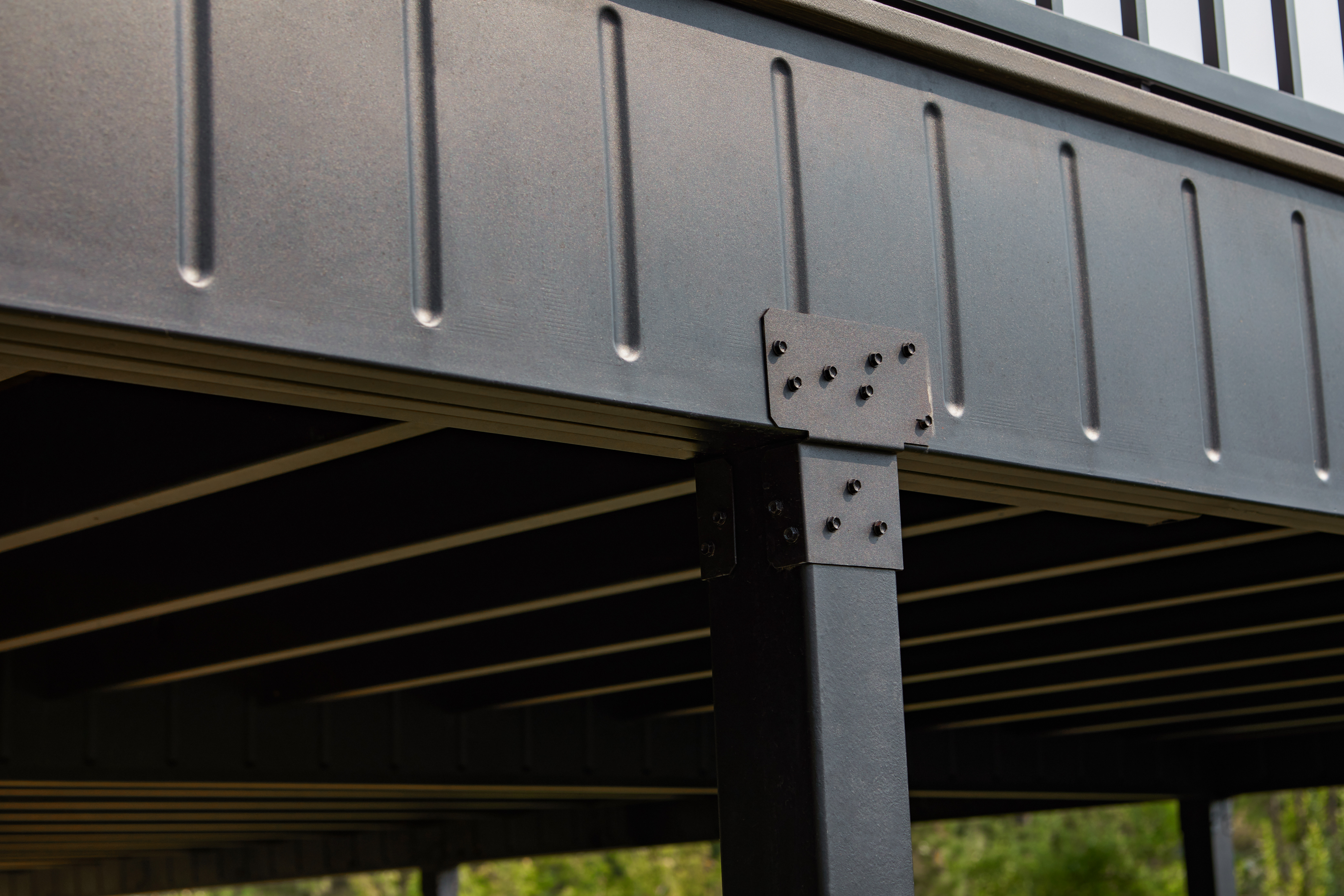 Close-up of weather-proof steel deck framing with bolted post bracket — built to last.