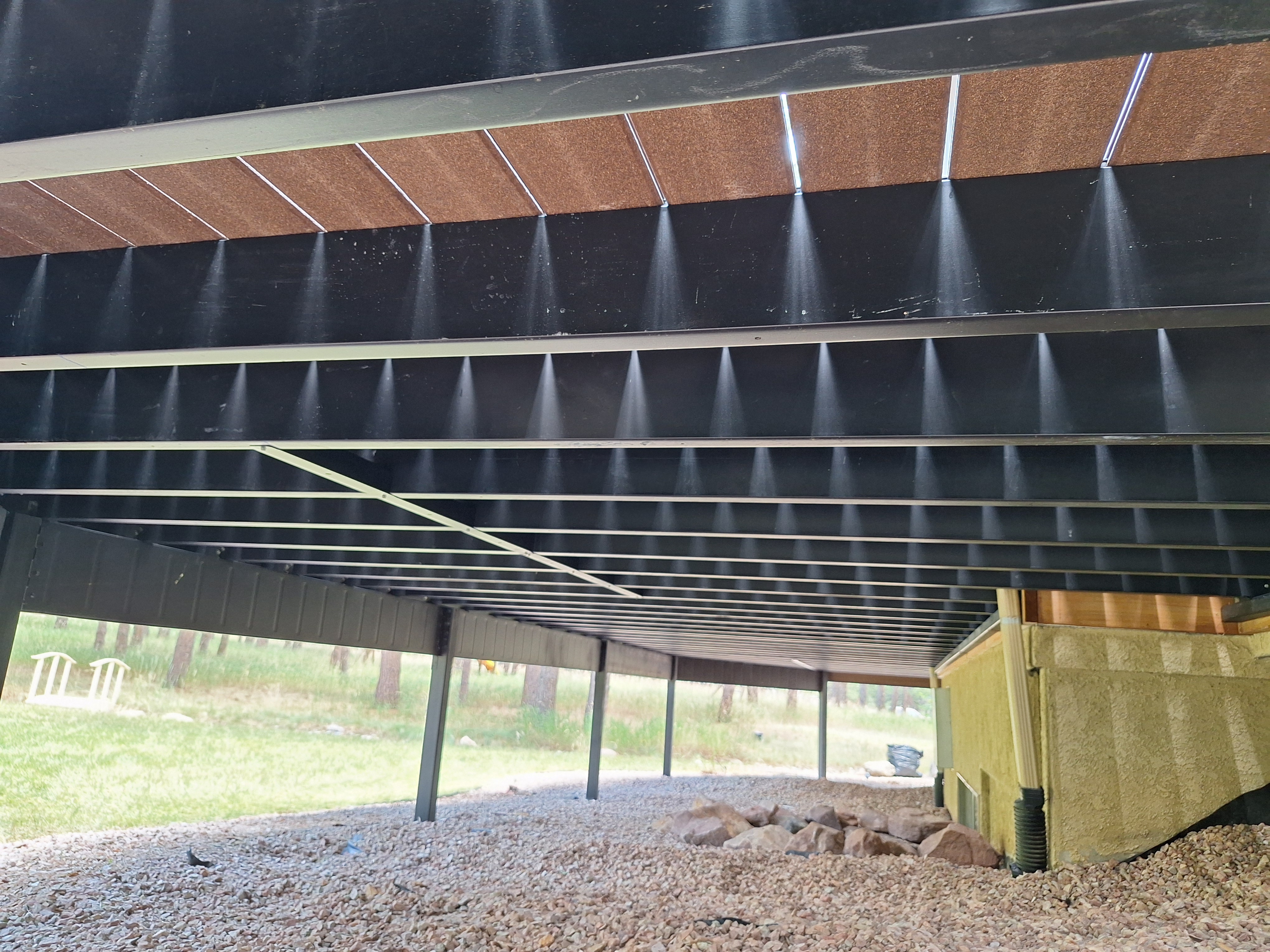 A wooden deck structure with a roof, showcasing a steel framing system for durability and support.