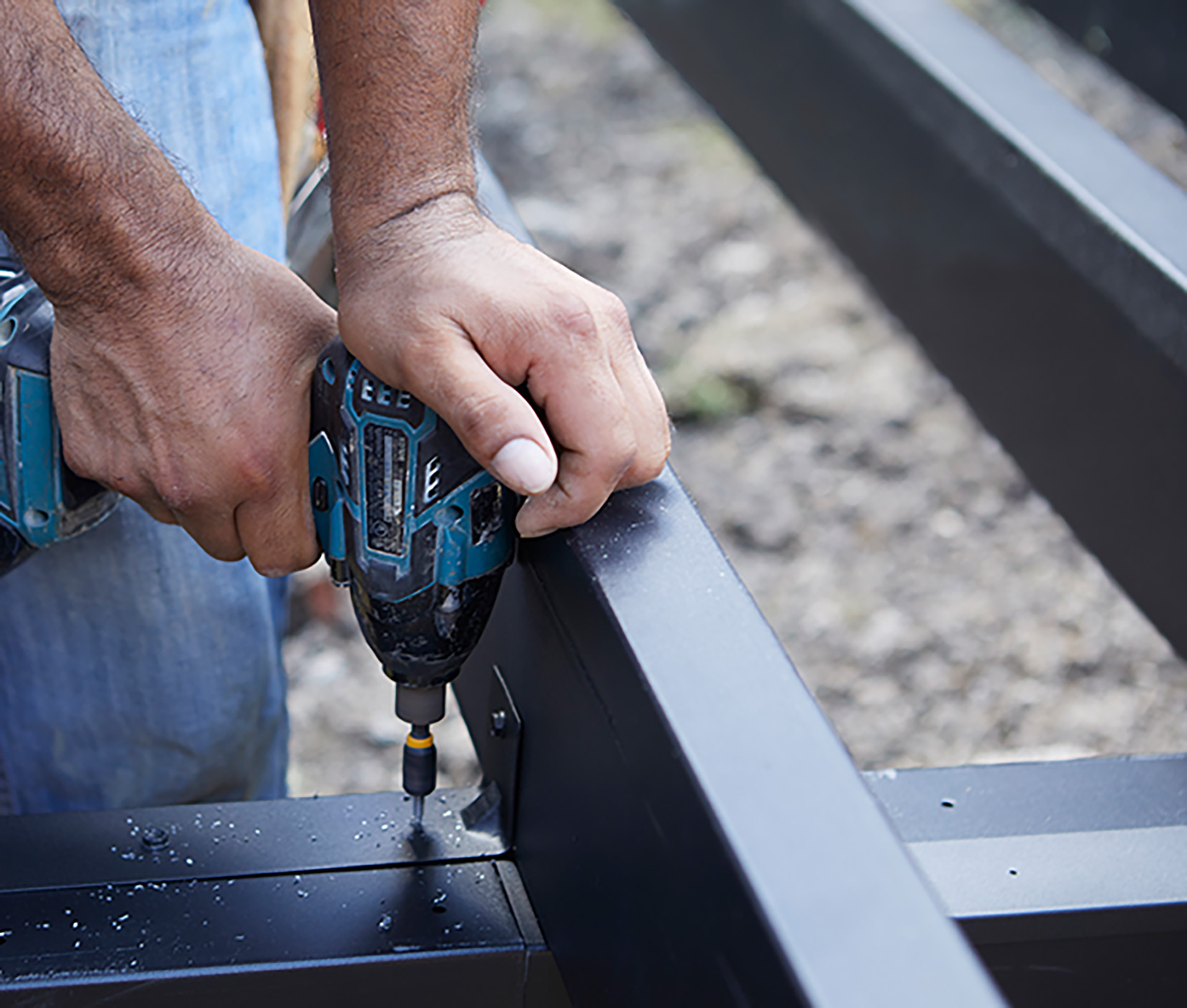 Close-up of a contractor securing steel deck framing with a power drill.