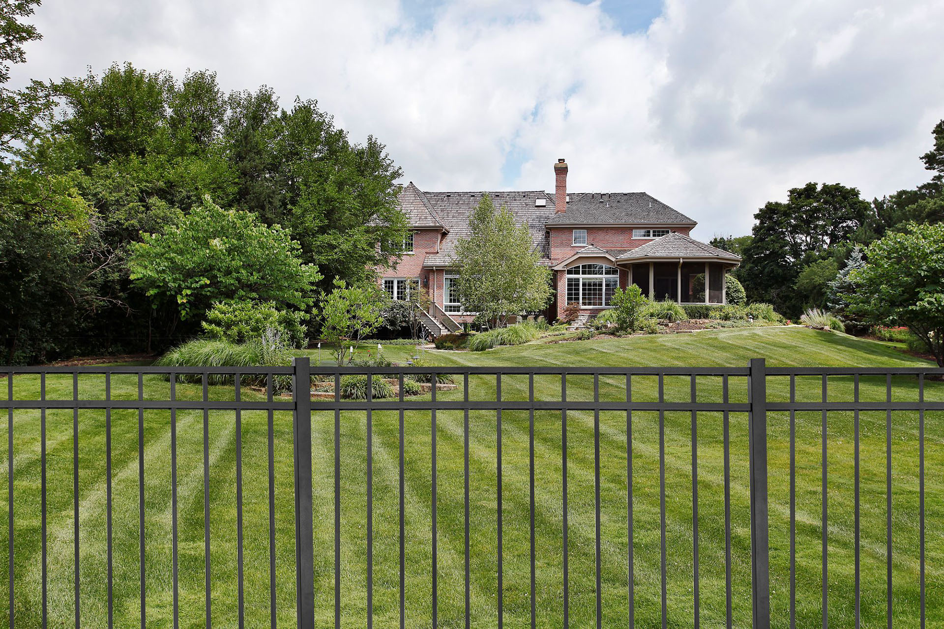 A black aluminum fence enclosing a large residential backyard.