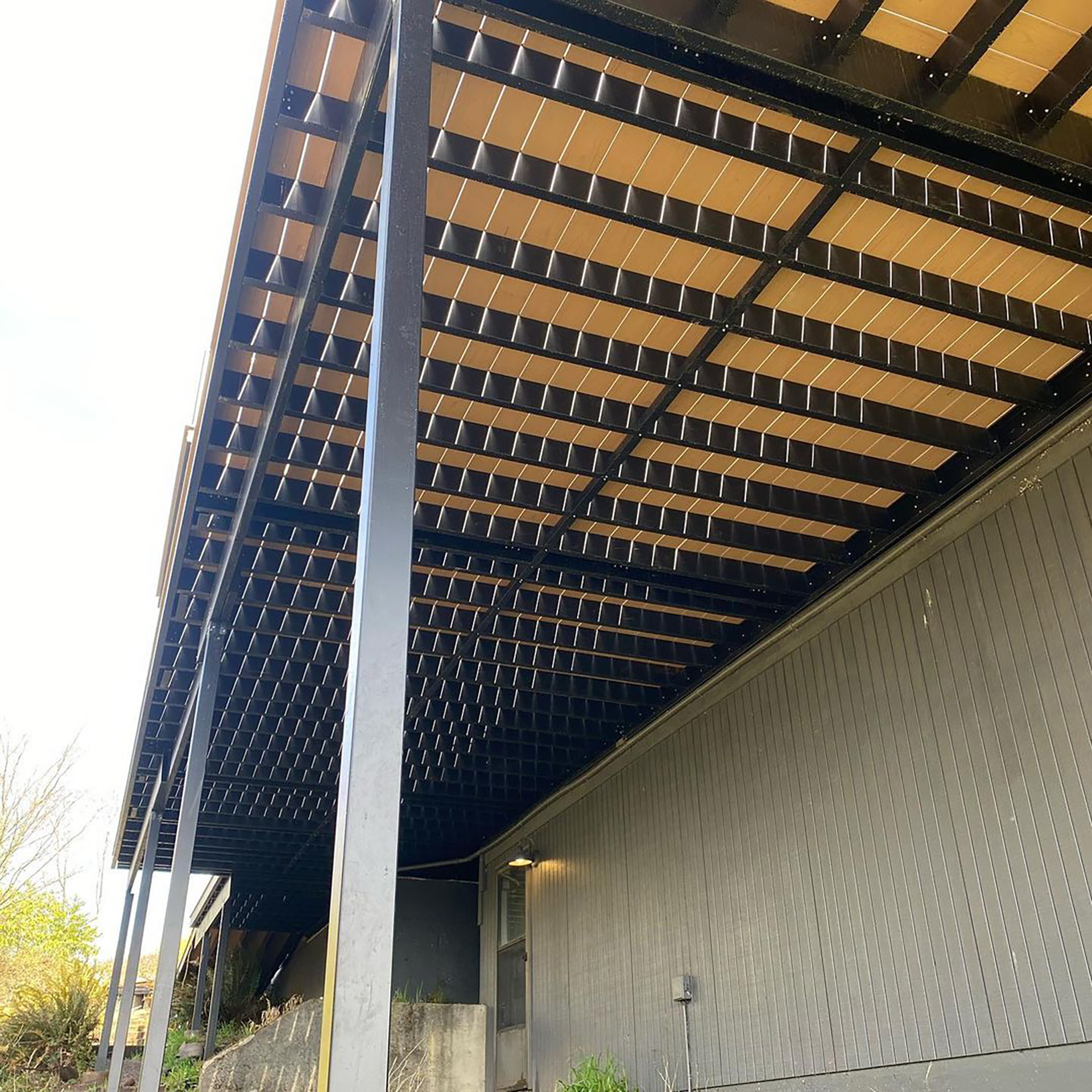 Underneath view of steel deck framing connected to a modern building.