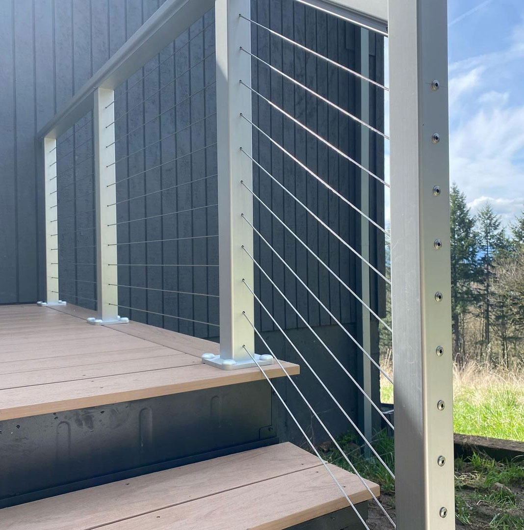 Close-up of a steel stair framing with modern cable railing on a wooden deck.