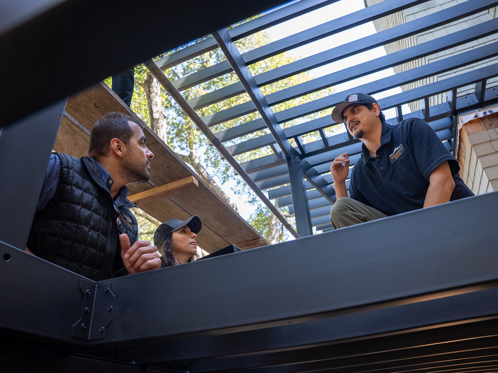 Contractors inspect Fortress steel framing installation below a raised deck during early construction phase.