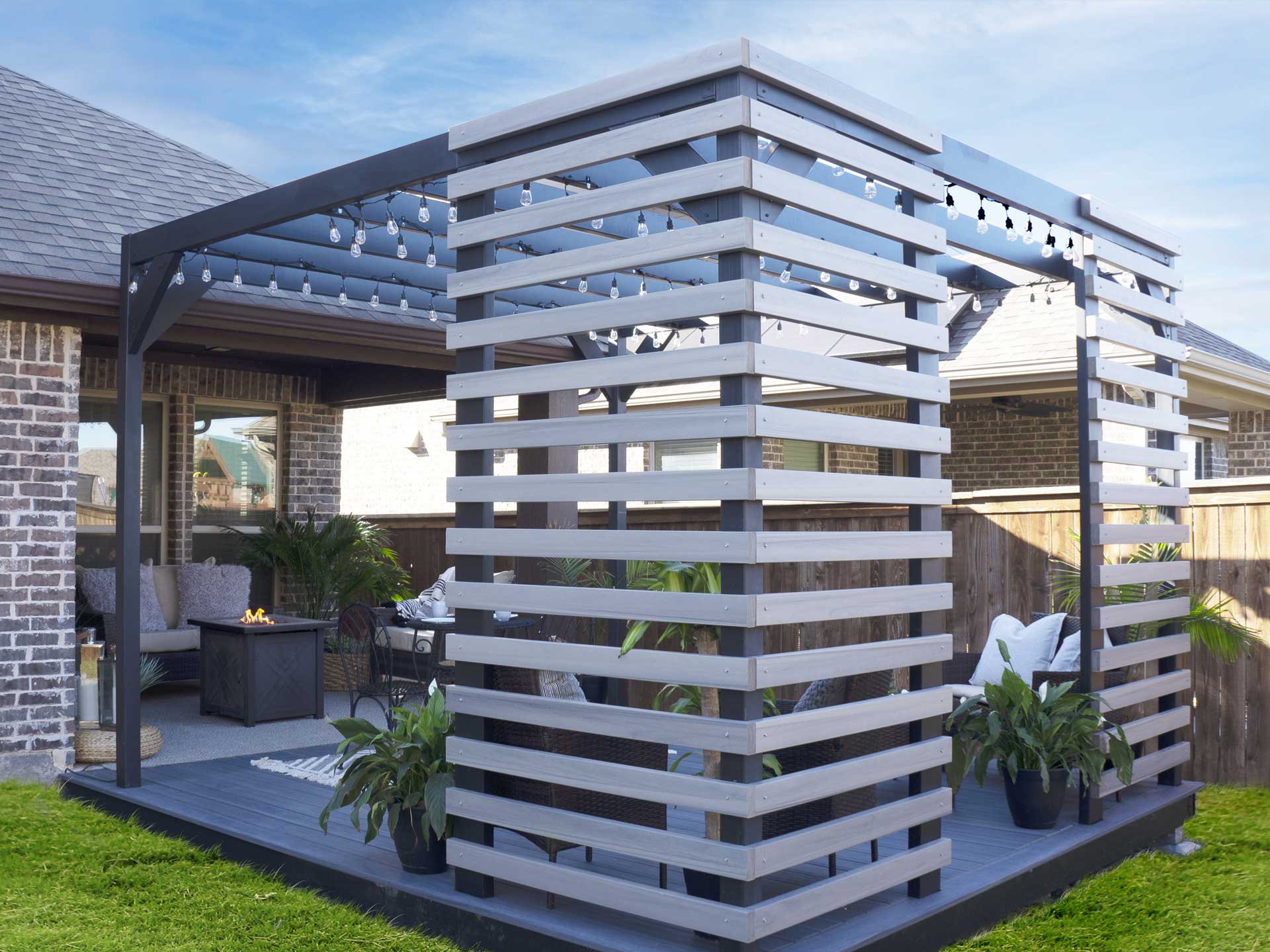 Modern backyard patio featuring a heavy-duty steel pergola with privacy screens and comfortable seating