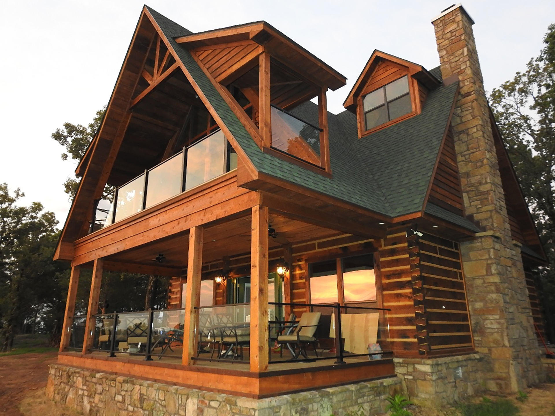 Rustic cabin with modern glass railing, blending contemporary and traditional architectural elements.