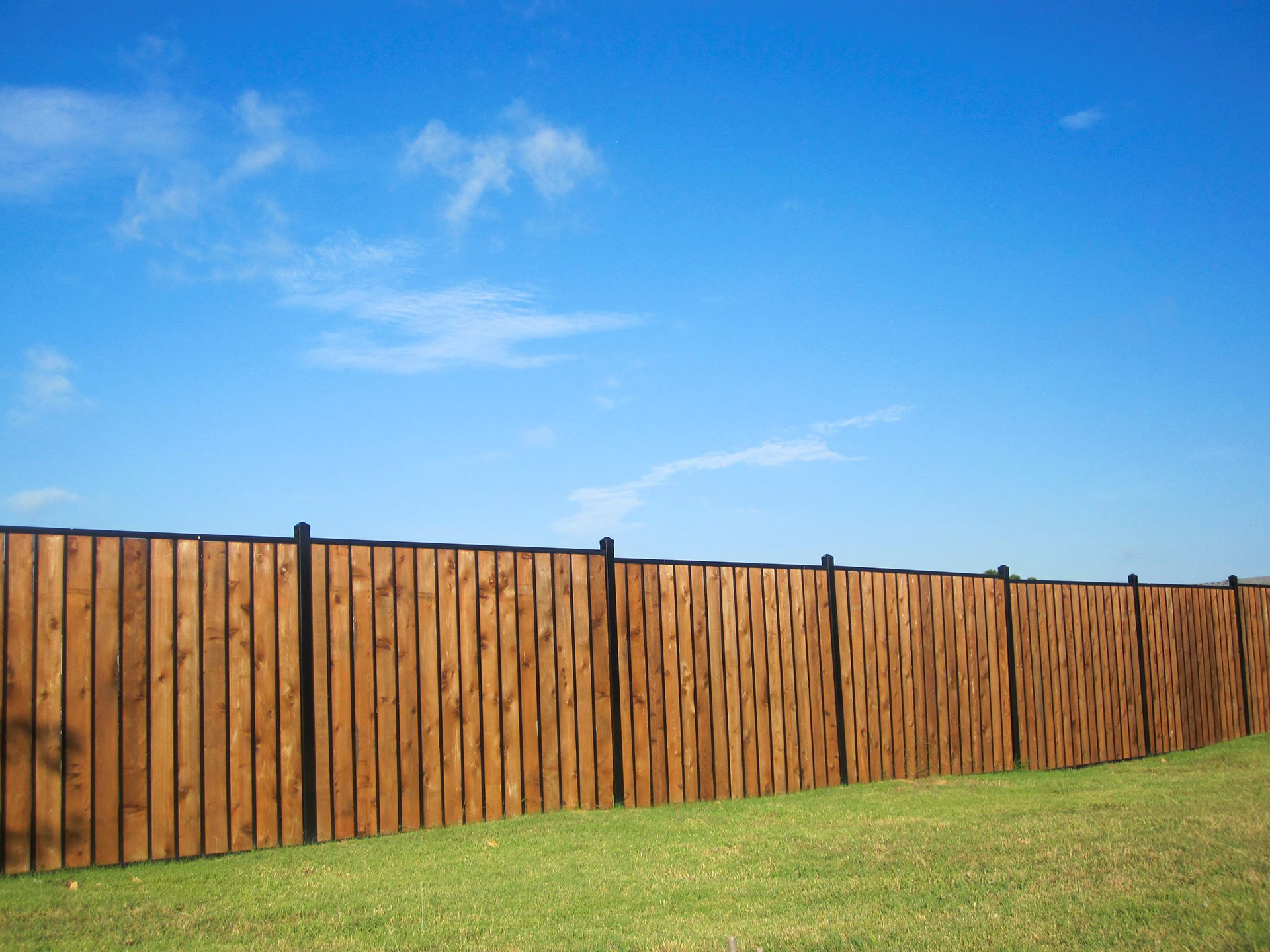 Wood-look privacy fence with black steel posts.