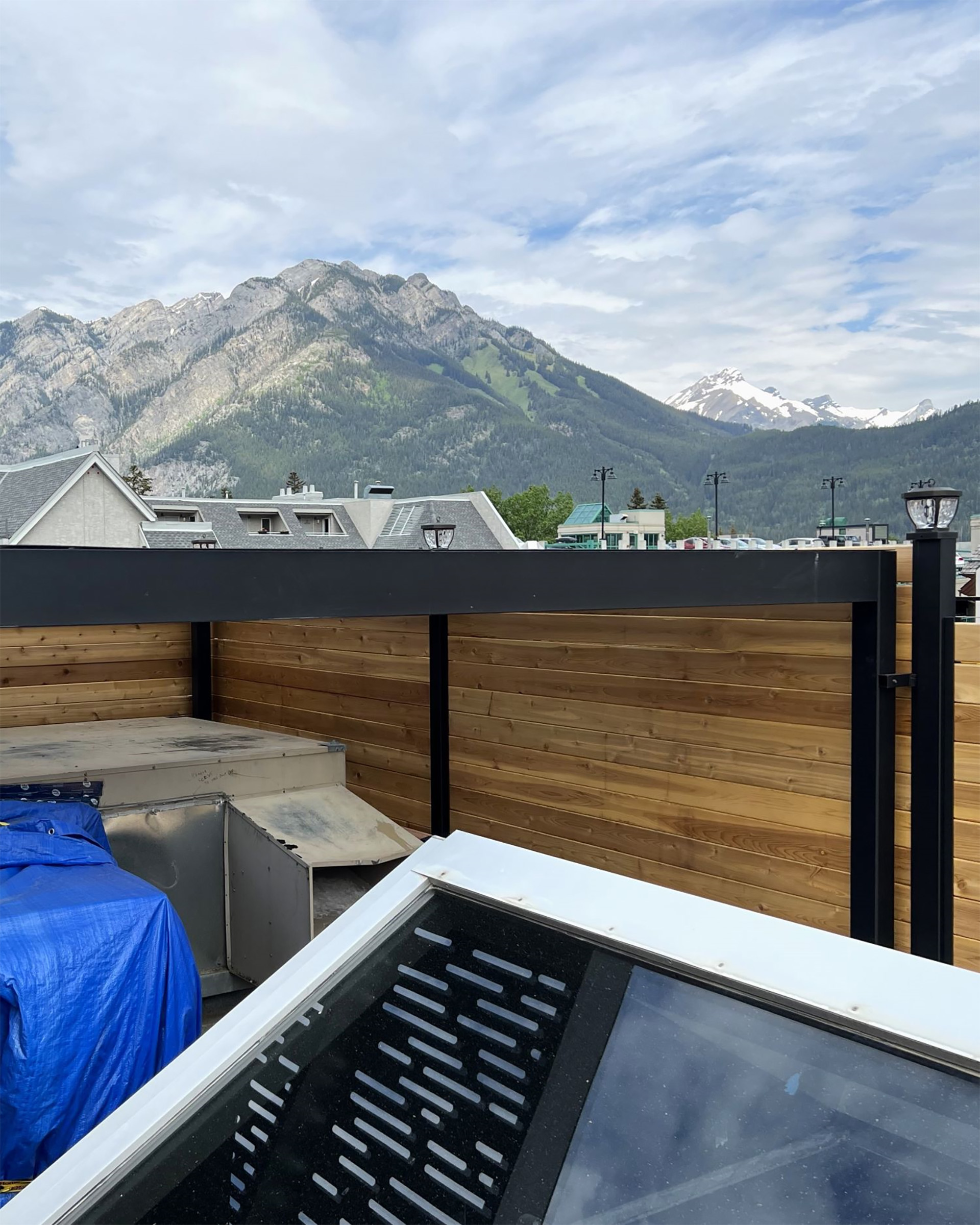 Steel pergola with wood privacy wall overlooking mountain scenery.