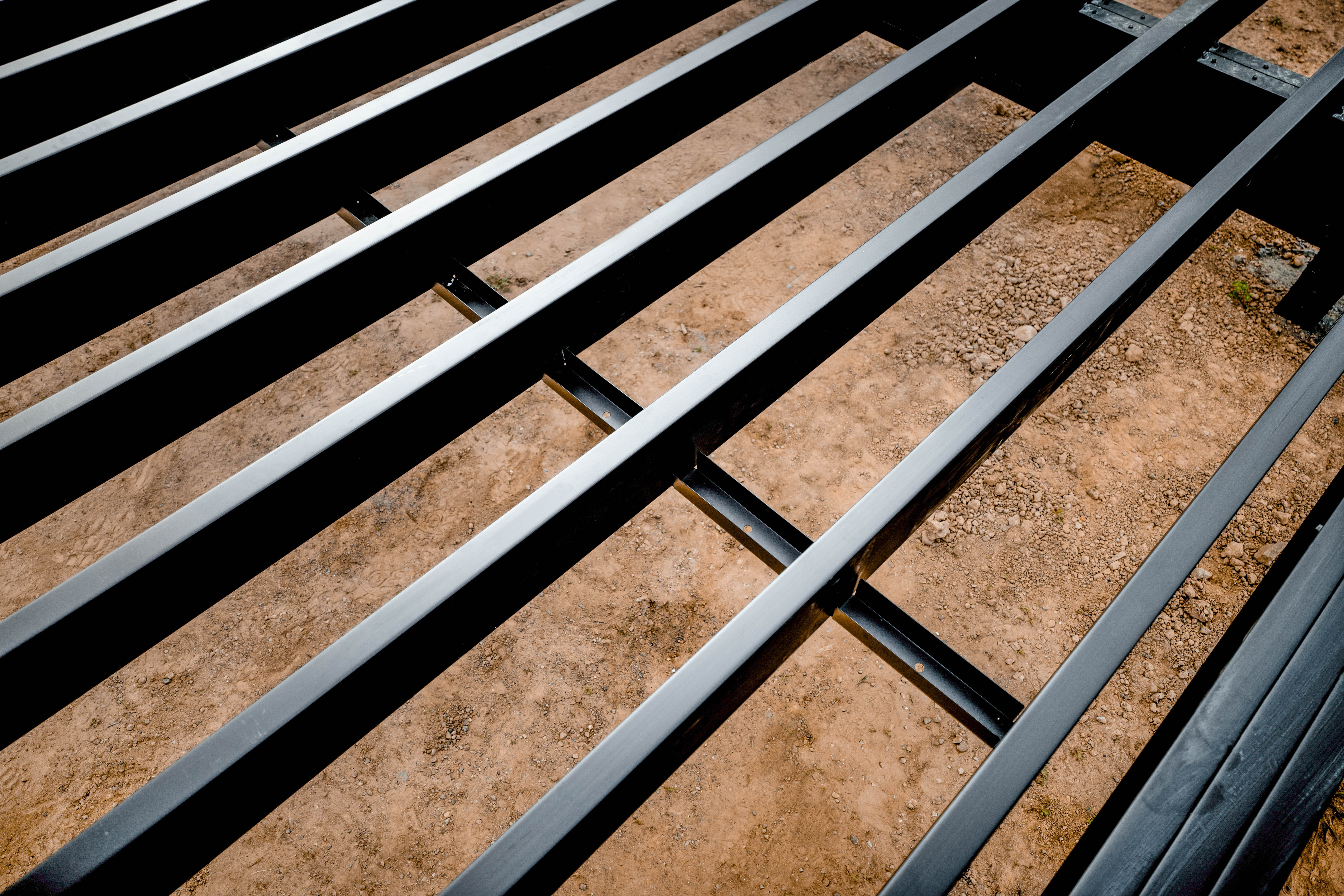 Close-up of a metal fence with bars on the ground, used in a steel deck framing system for building decks.
