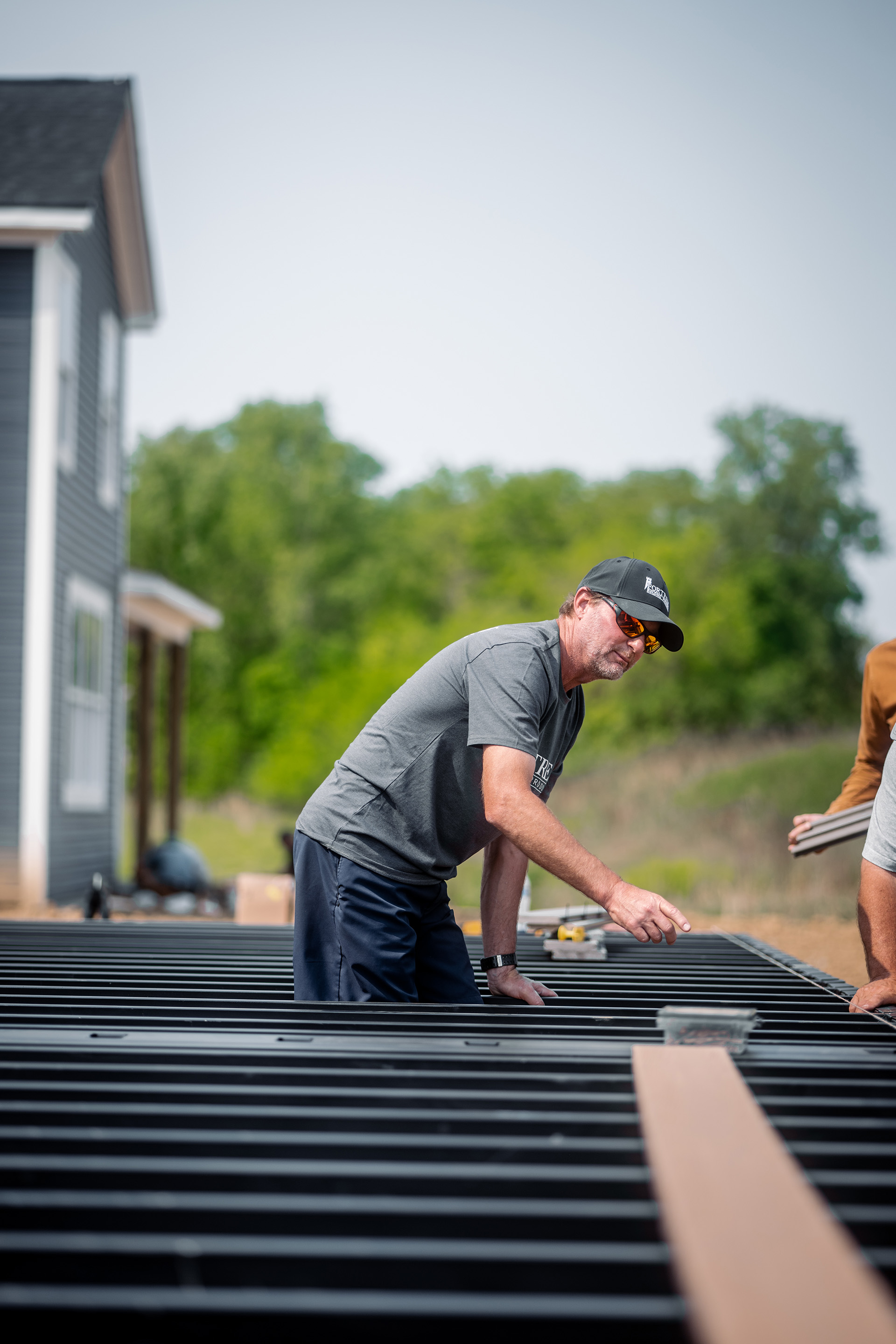 Contractor manually adjusting steel deck framing at a residential construction site.