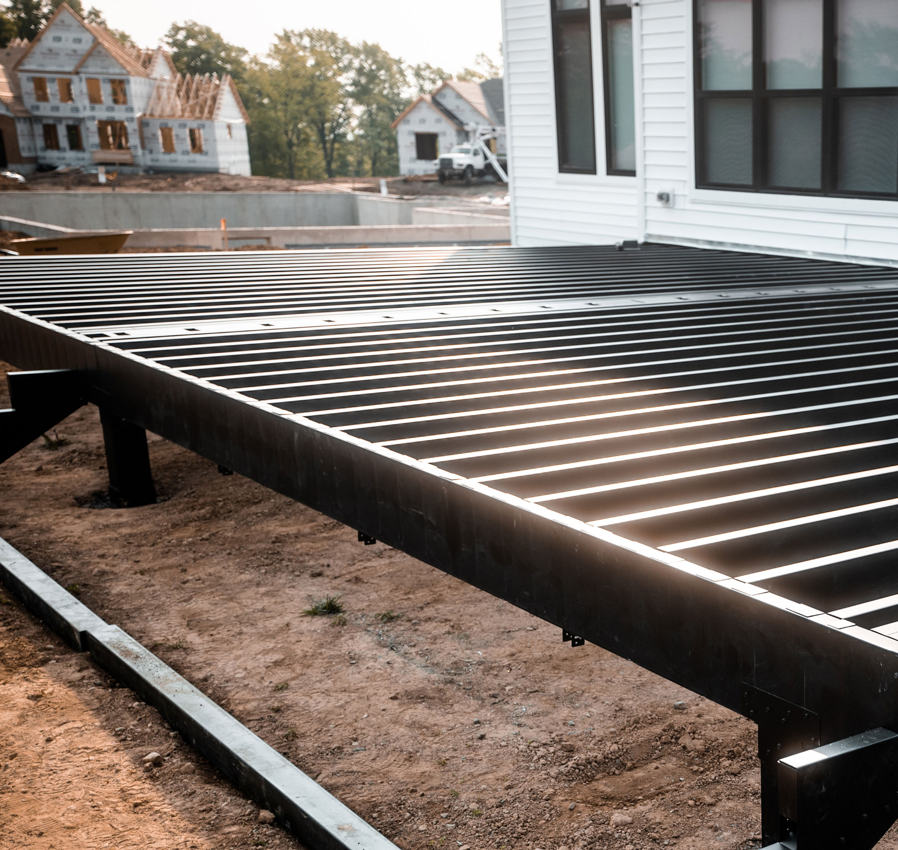 Steel stair framing construction at a residential site with multiple homes in the background.