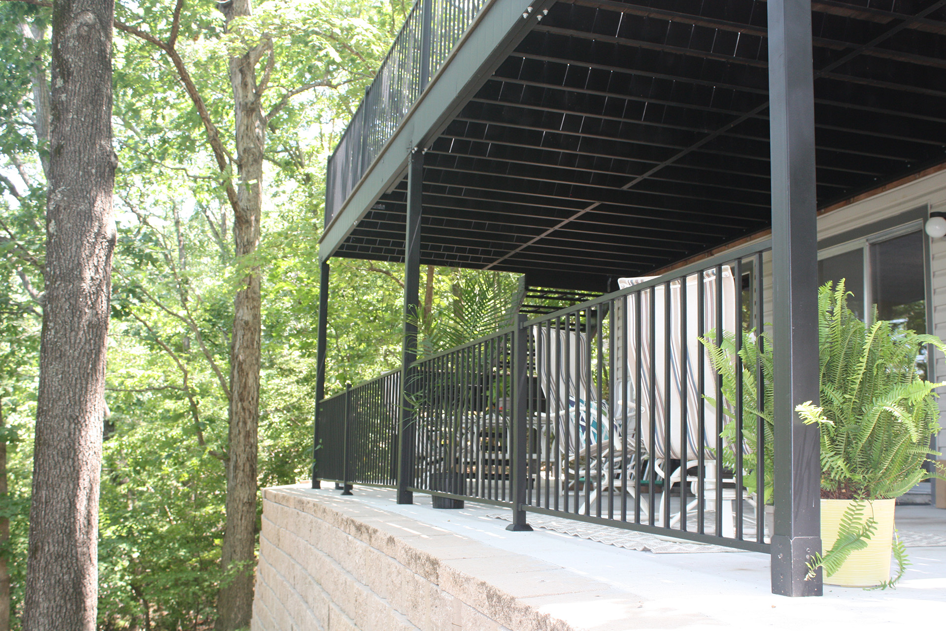 A balcony with a fireproof deck, showcasing a railing and a vibrant potted plant for a welcoming outdoor atmosphere.