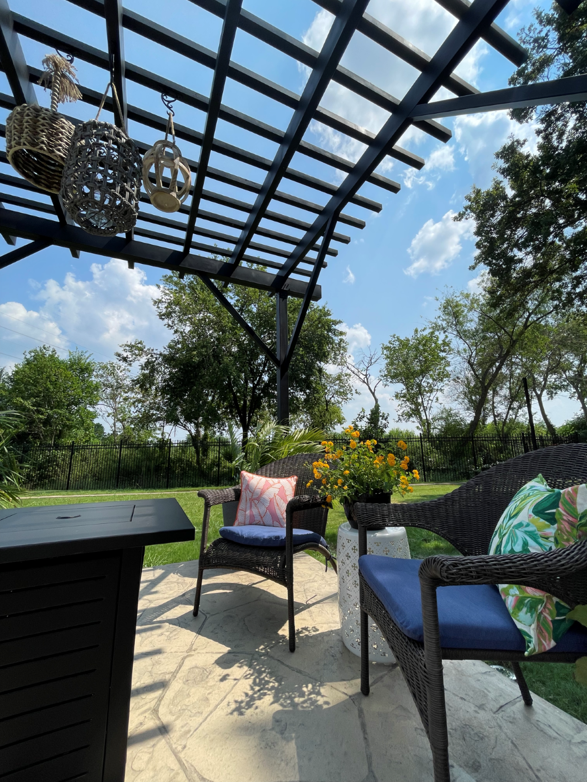 Close up view of an outdoor pergola over a sitting area with trees in the background.
