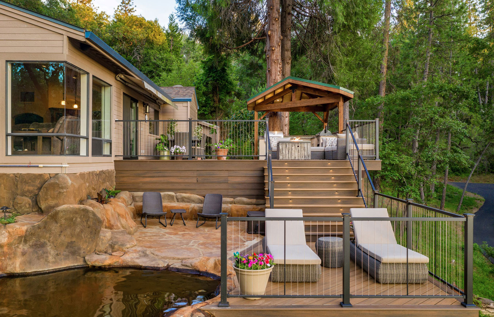 Cable railing enclosing a multi-level deck with patio furniture and a rock swimming pool.