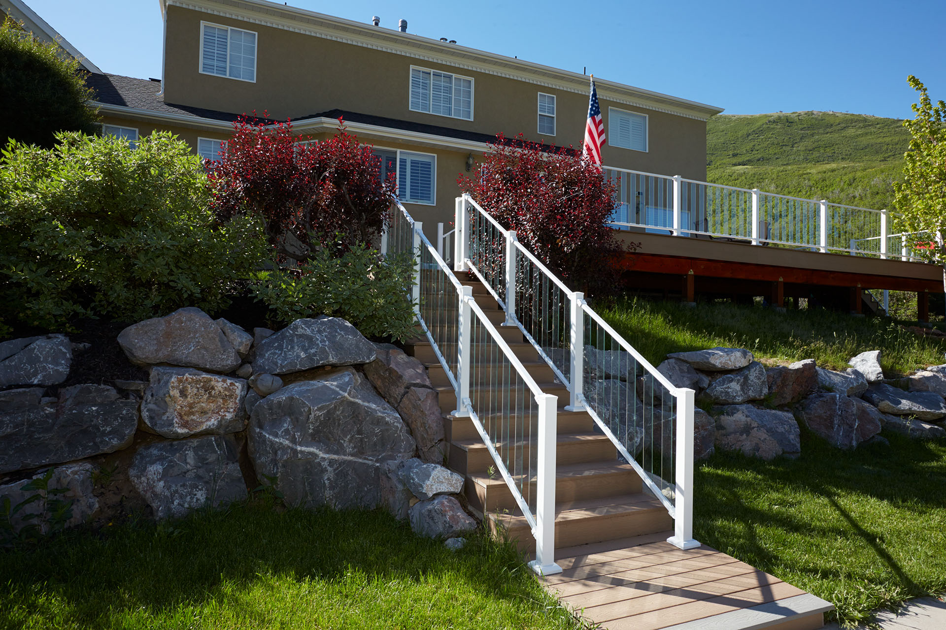 White stair railings with glass panels lining a hillside deck.
