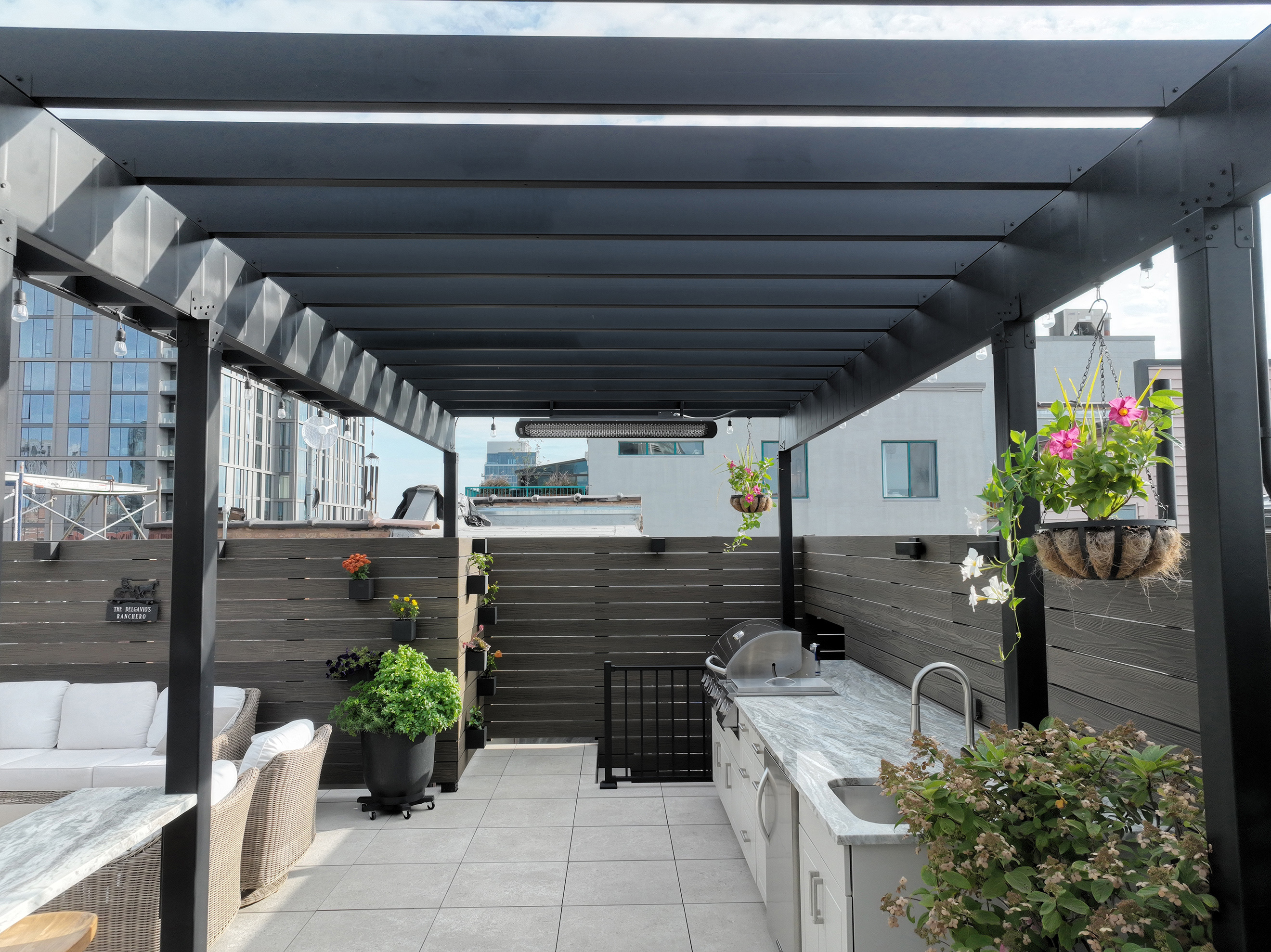 A weatherproof rooftop deck with a pergola and grill, ideal for outdoor gatherings and cooking.