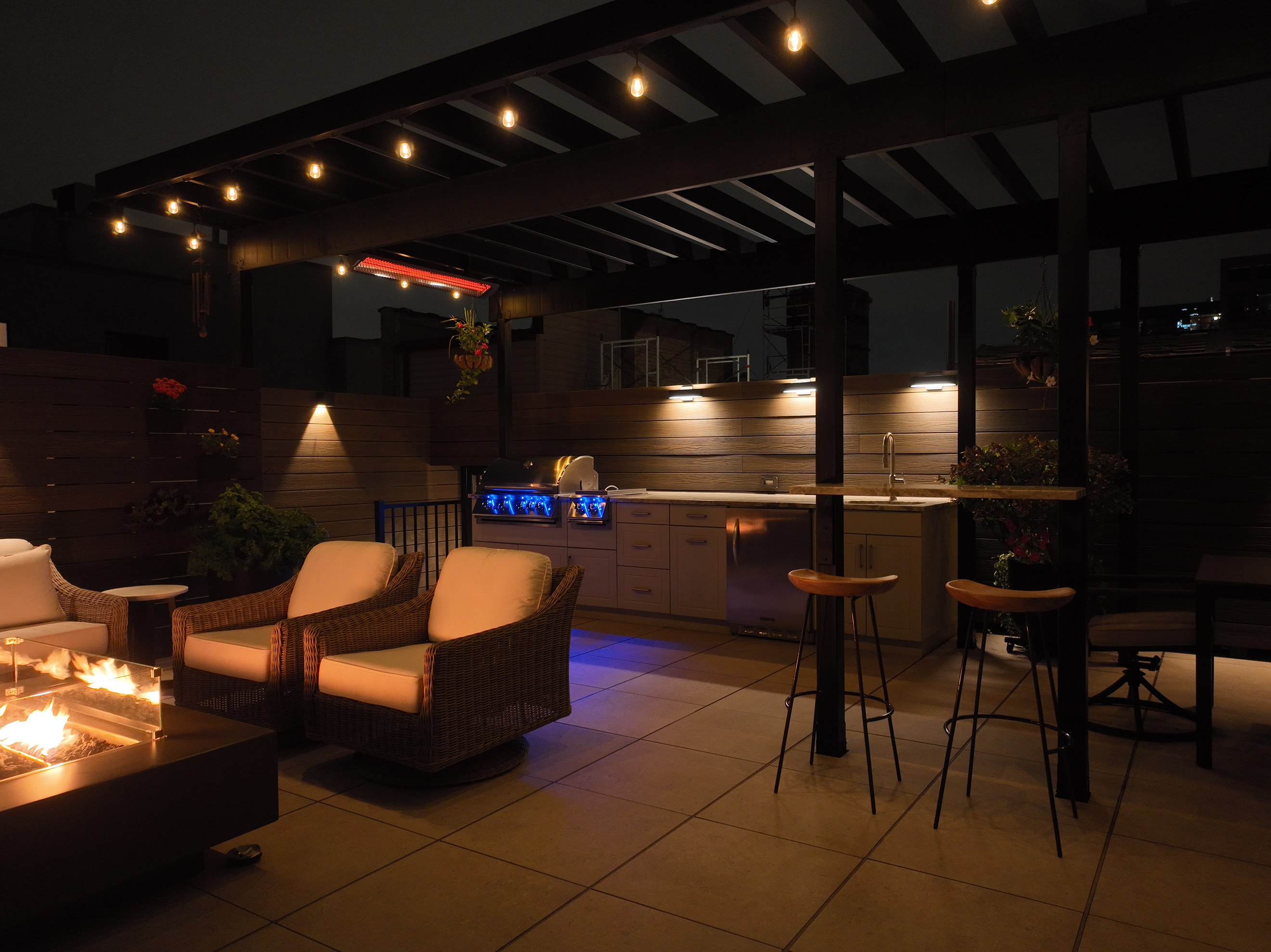 A rooftop patio featuring a fire pit surrounded by weatherproof chairs on a fireproof deck.